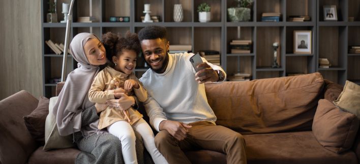 Delighted multiethnic family taking selfie sitting on couch