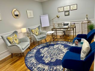 Crop anonymous African American man in casual clothes sitting on sofa and talking to female psychologist during psychotherapy session in modern studio